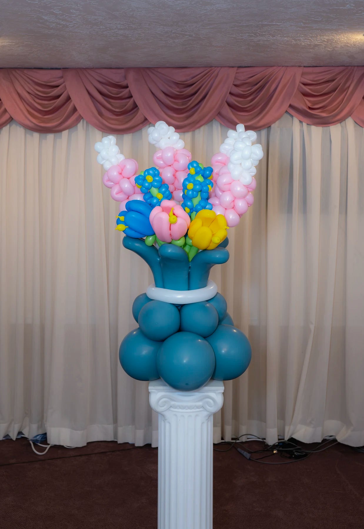 Mixed-color balloon flower bouquet arranged in a blue balloon vase.
