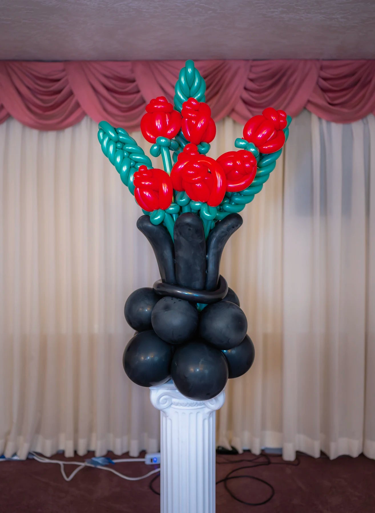 Red balloon rose bouquet arranged in a black balloon vase.