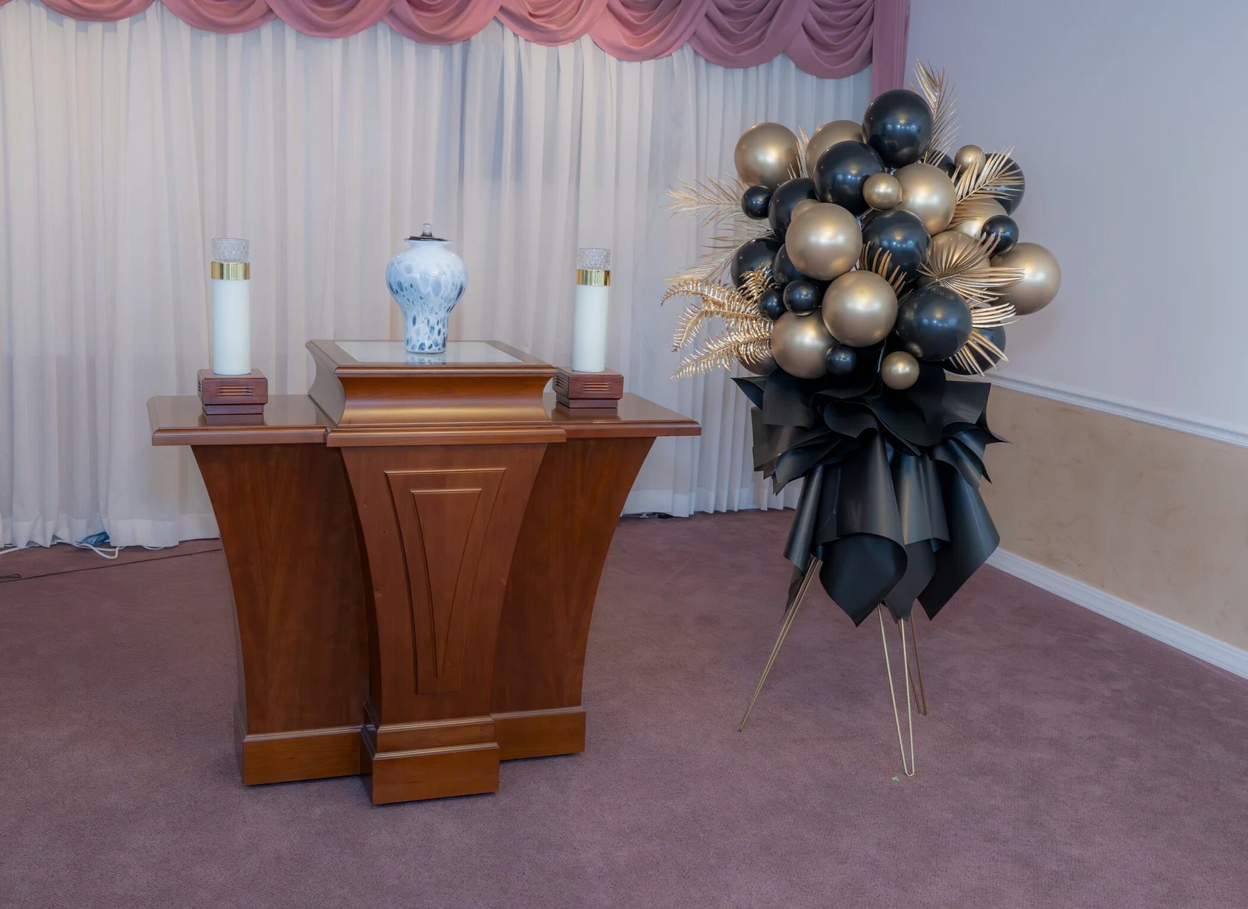 Black, bronze, and gold memorial standing arrangement near a pulpit.