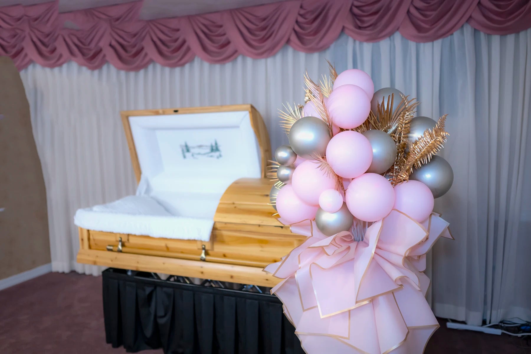 Blush and champagne memorial standing arrangement beside a casket.