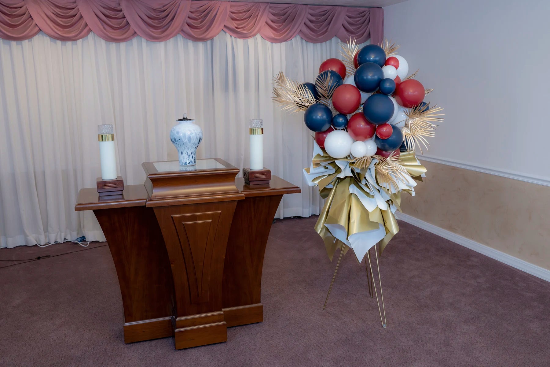 Red, blue, and gold memorial standing arrangement near a pulpit.