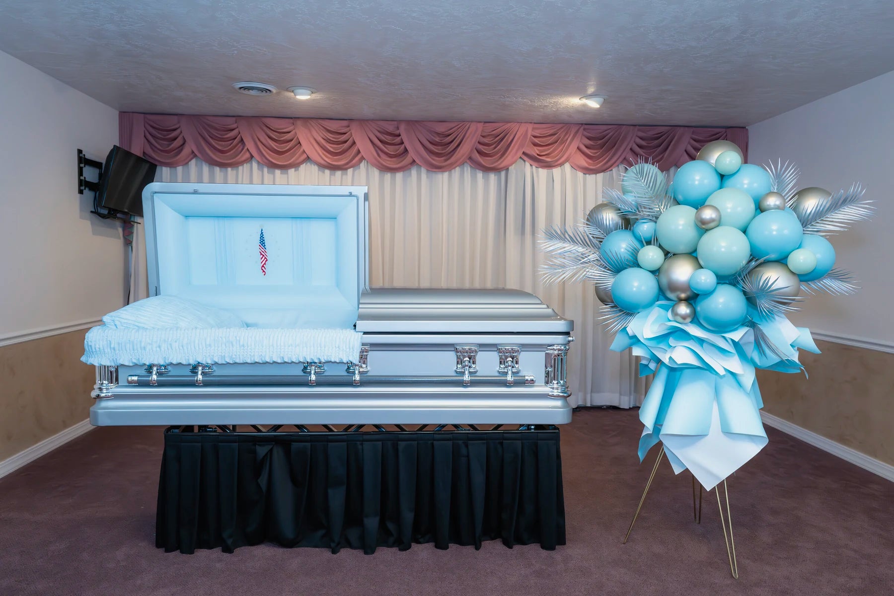 Silver and blue memorial standing arrangement placed beside a casket.